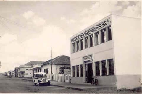Foto antiga de um prédio de dois andares do Banco Mercantil e Industrial do Paraná numa rua de terra